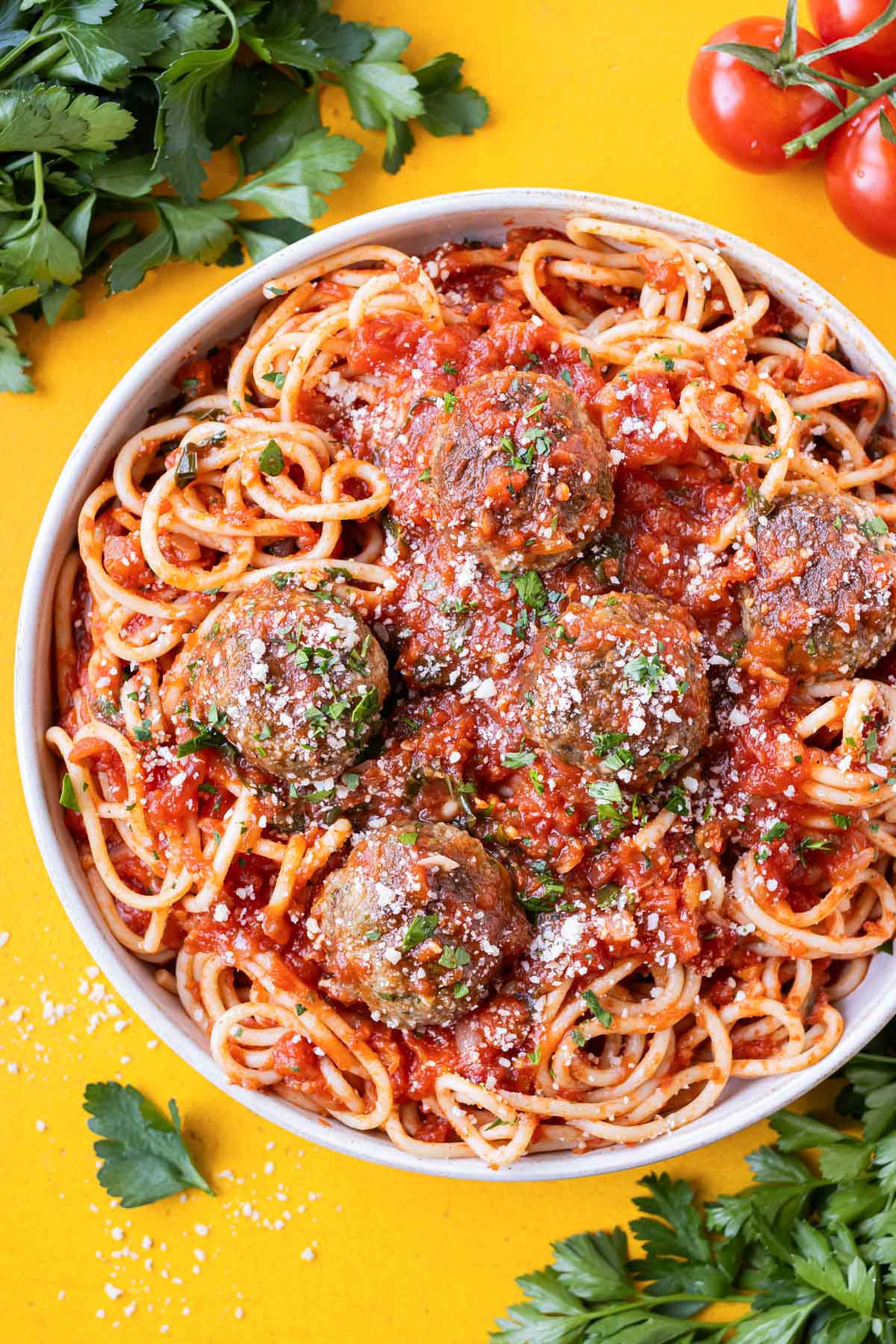 A big bowl of spaghetti and easy Italian meatballs is served with Parmesan cheese.