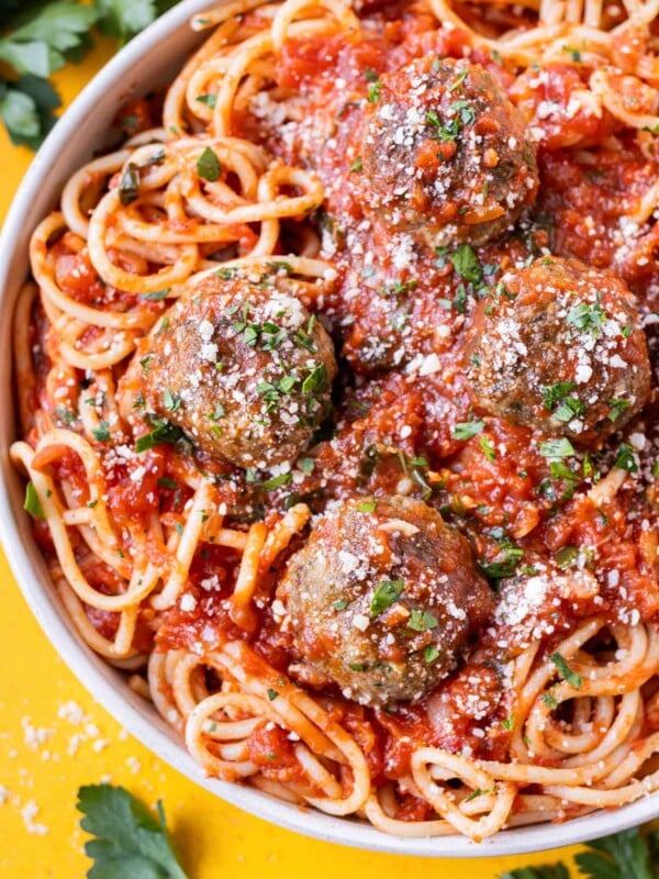 A bowl of spaghetti and marinara sauce with four Italian meatballs with Parmesan cheese.