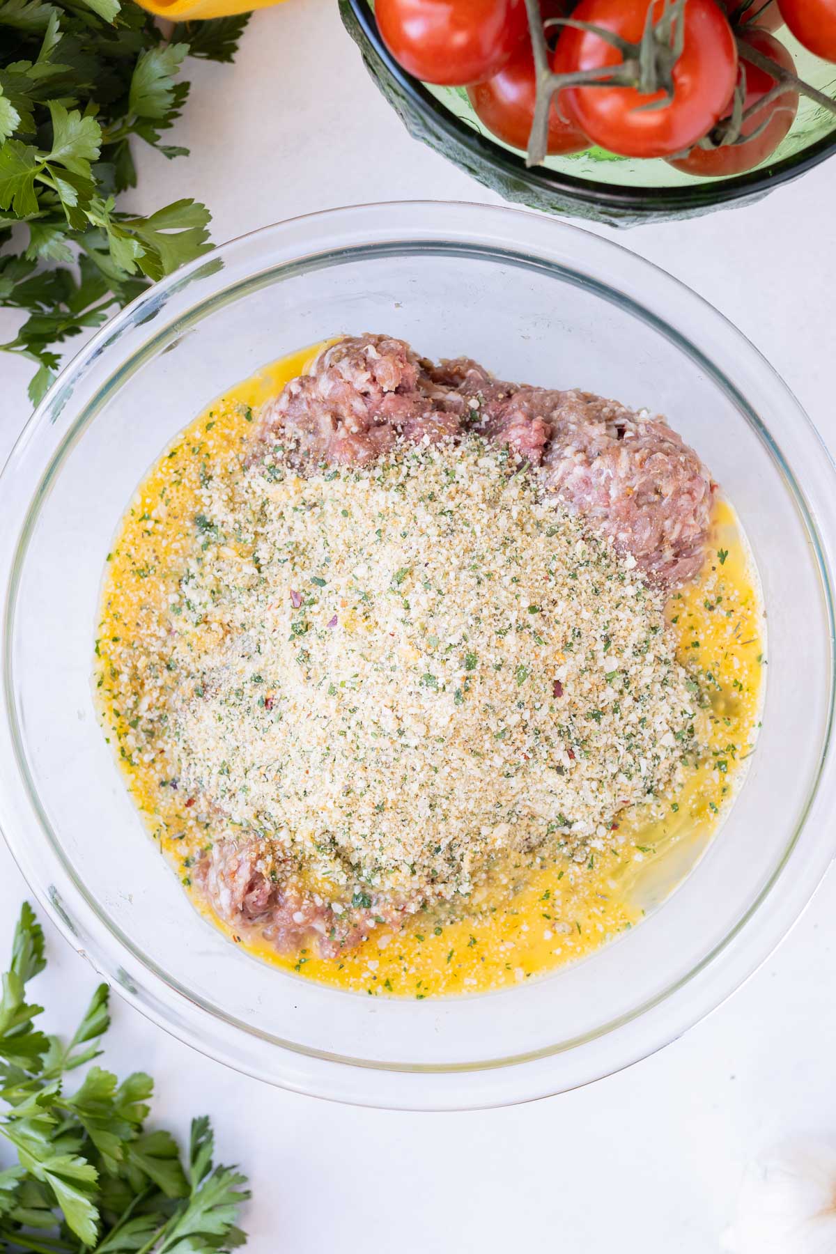Ground beef, pork, breadcrumbs, an egg, and seasonings are combined in a bowl for an easy meatballs recipe.