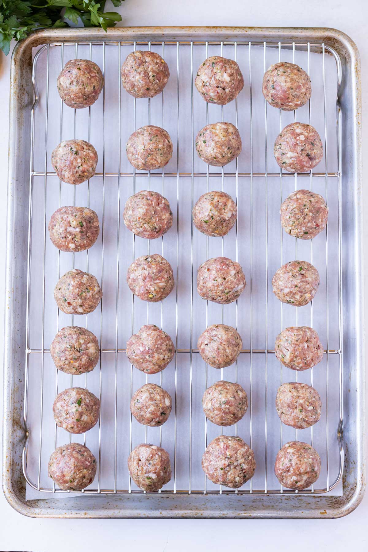A baking sheet with a wire rack and Italian meatballs placed on top.