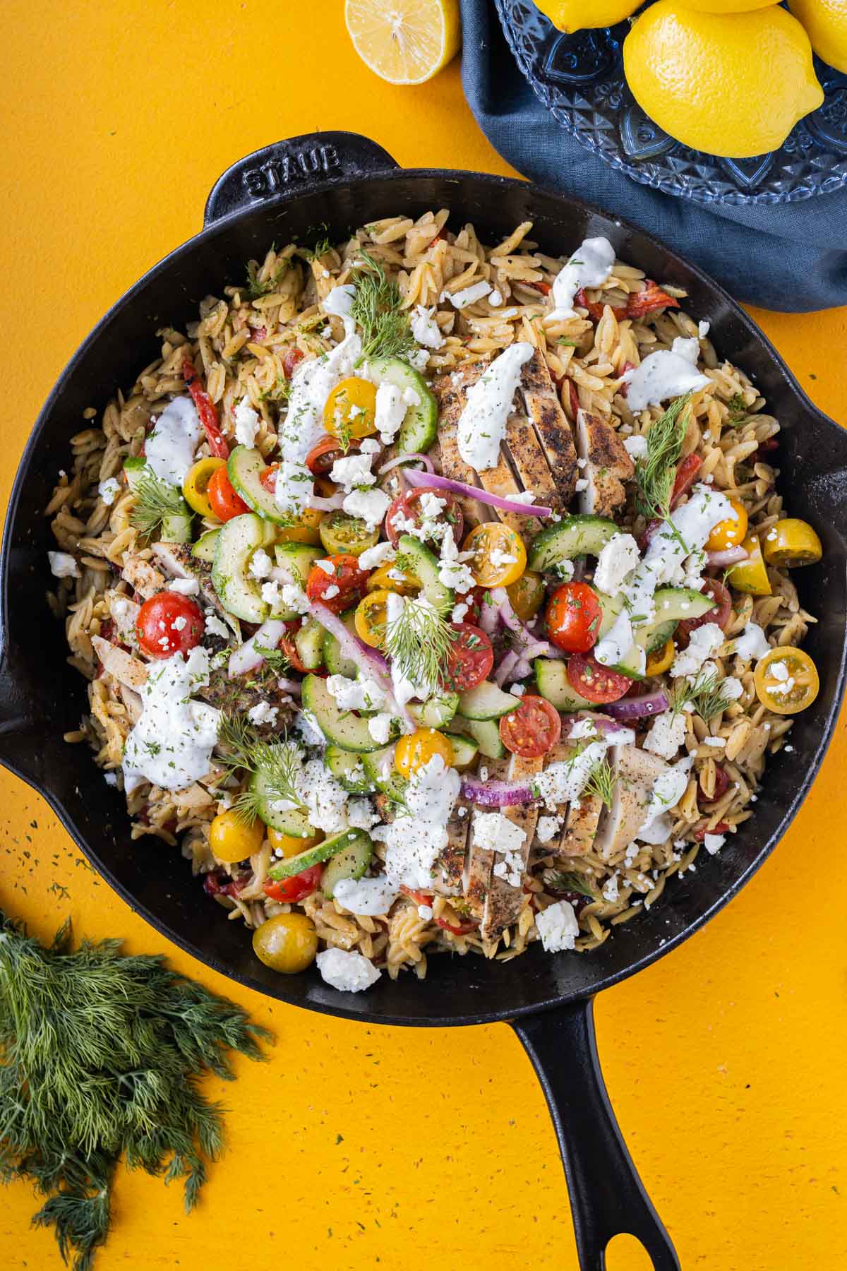 A Mediterranean Shawarma Chicken Orzo one-skillet recipe is served for dinner with cucumber salad and a dill yogurt sauce.