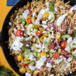 A Greek Shawarma Chicken Orzo Skillet with cucumber salad and a dill yogurt sauce is served for dinner.