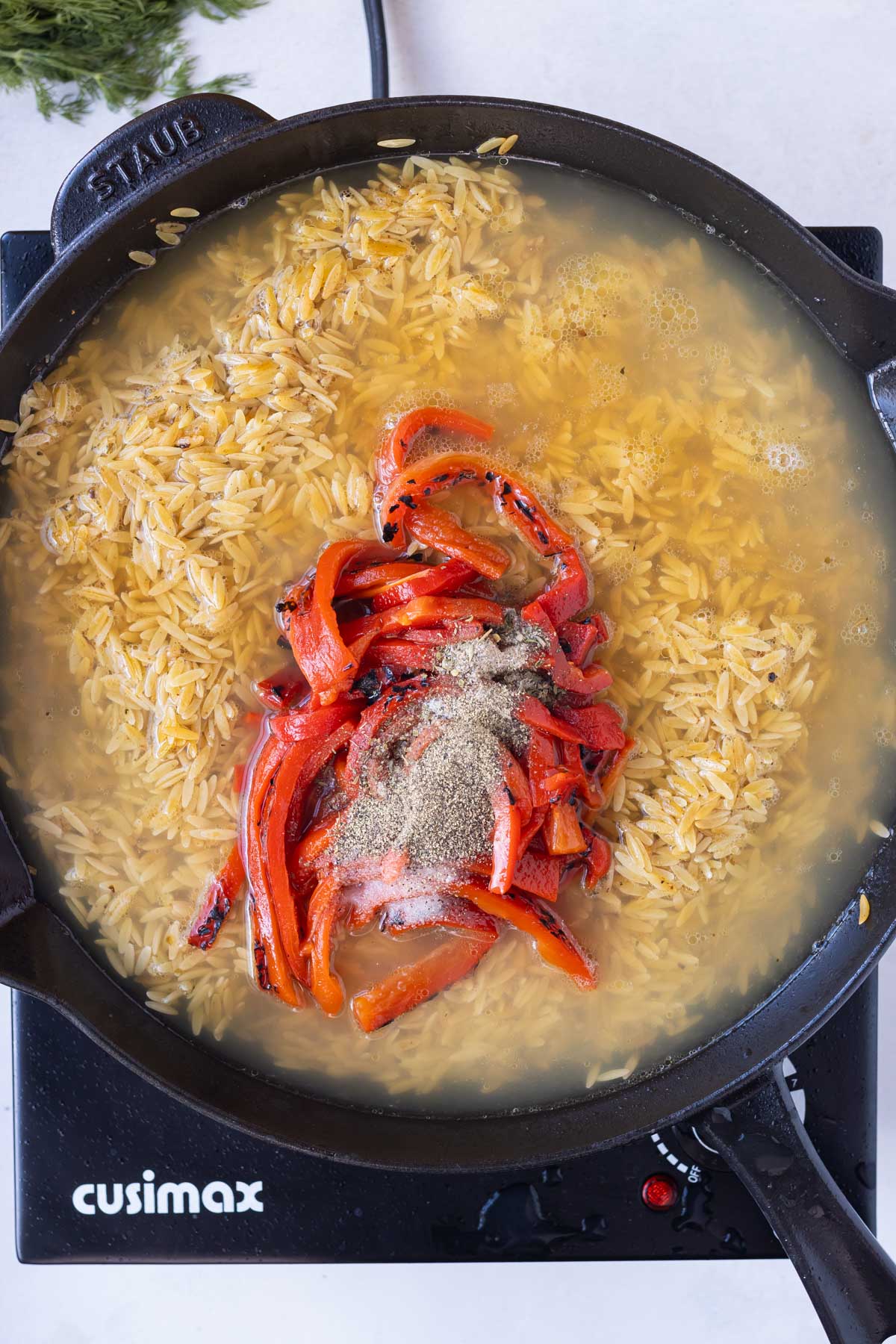 Broth is added to the orzo with some roasted red peppers.