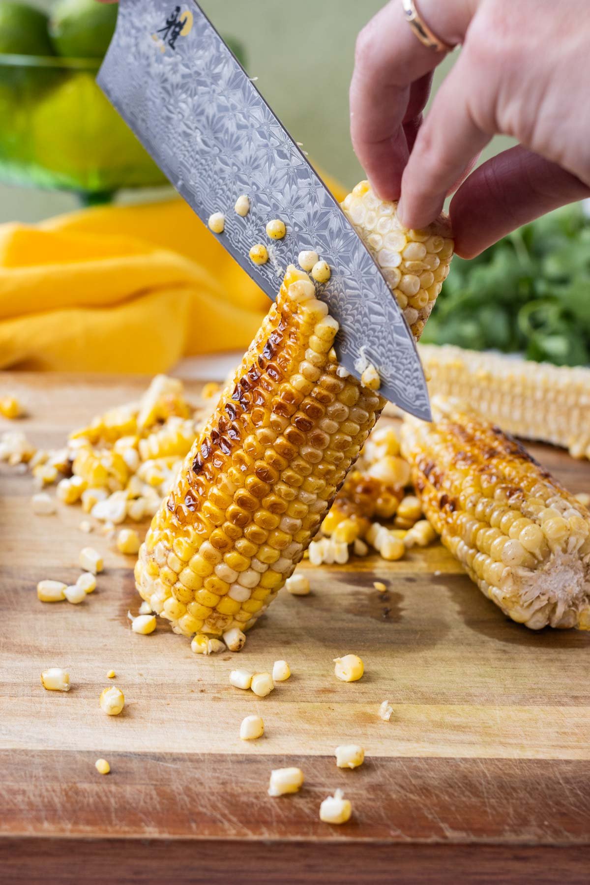 A knife cuts the kernels of corn off the cob.