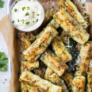 Crispy Parmesan crusted zucchini is served in a tray with a lemon garlic aioli on the side.