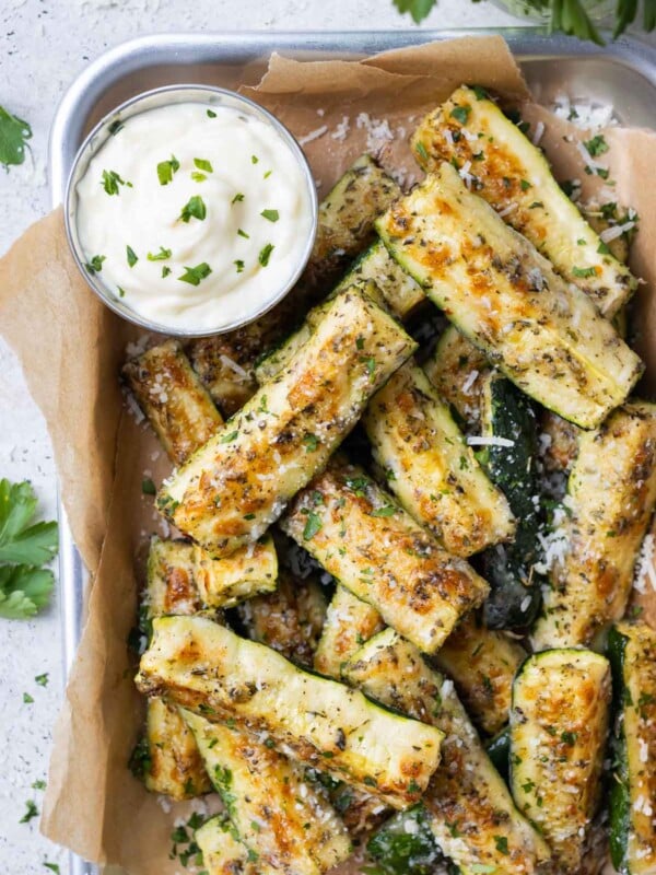 Crispy Parmesan crusted zucchini is served in a tray with a lemon garlic aioli on the side.