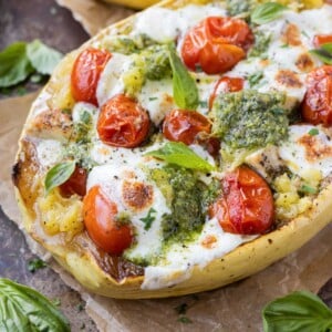 A Pesto Chicken Stuffed Spaghetti Squash is served with mozzarella and roasted cherry tomatoes.