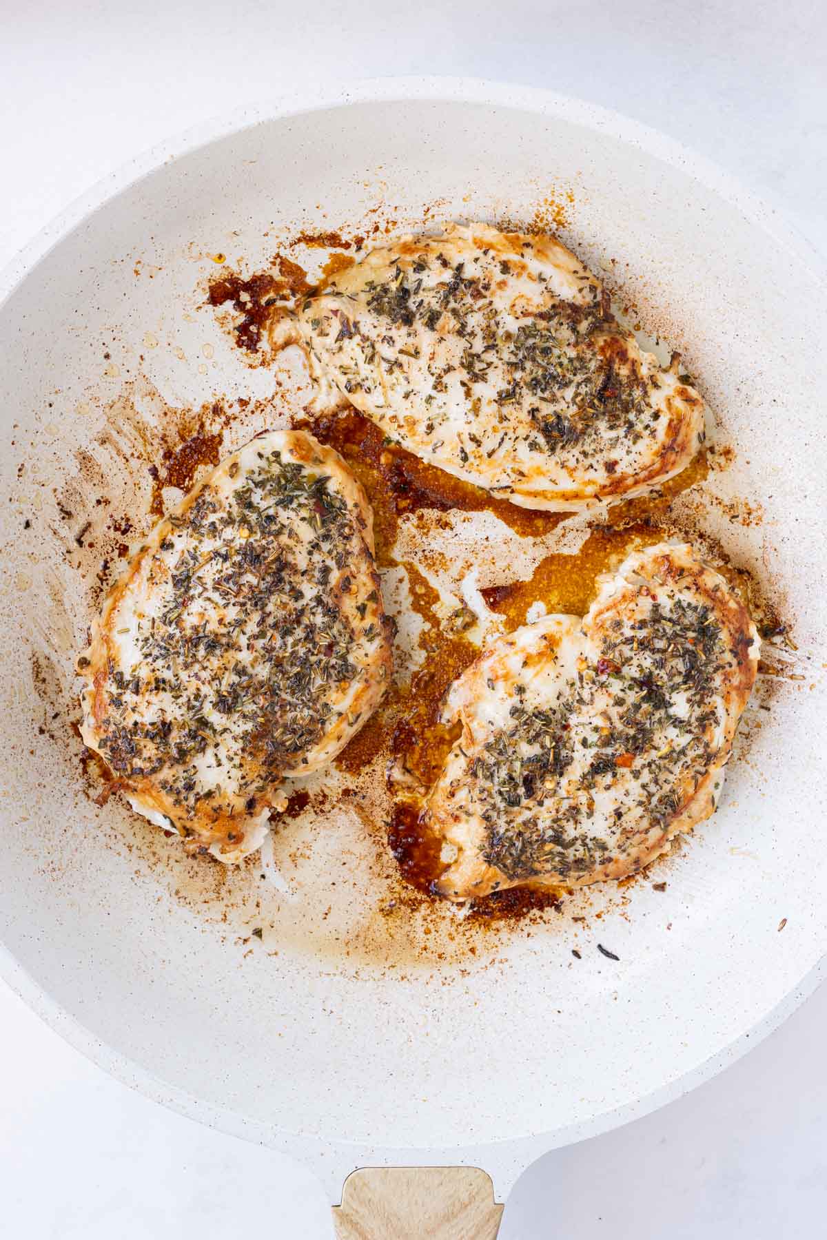 Seasoned chicken is cooked in a skillet.