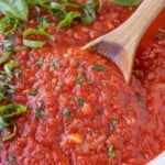 San Marzano tomato sauce is being stirred in a skillet with a wooden spoon.
