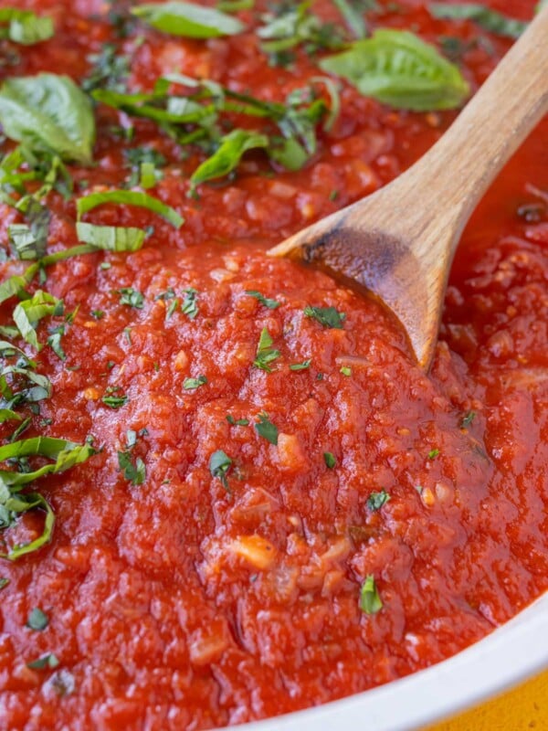 San Marzano tomato sauce is being stirred in a skillet with a wooden spoon.
