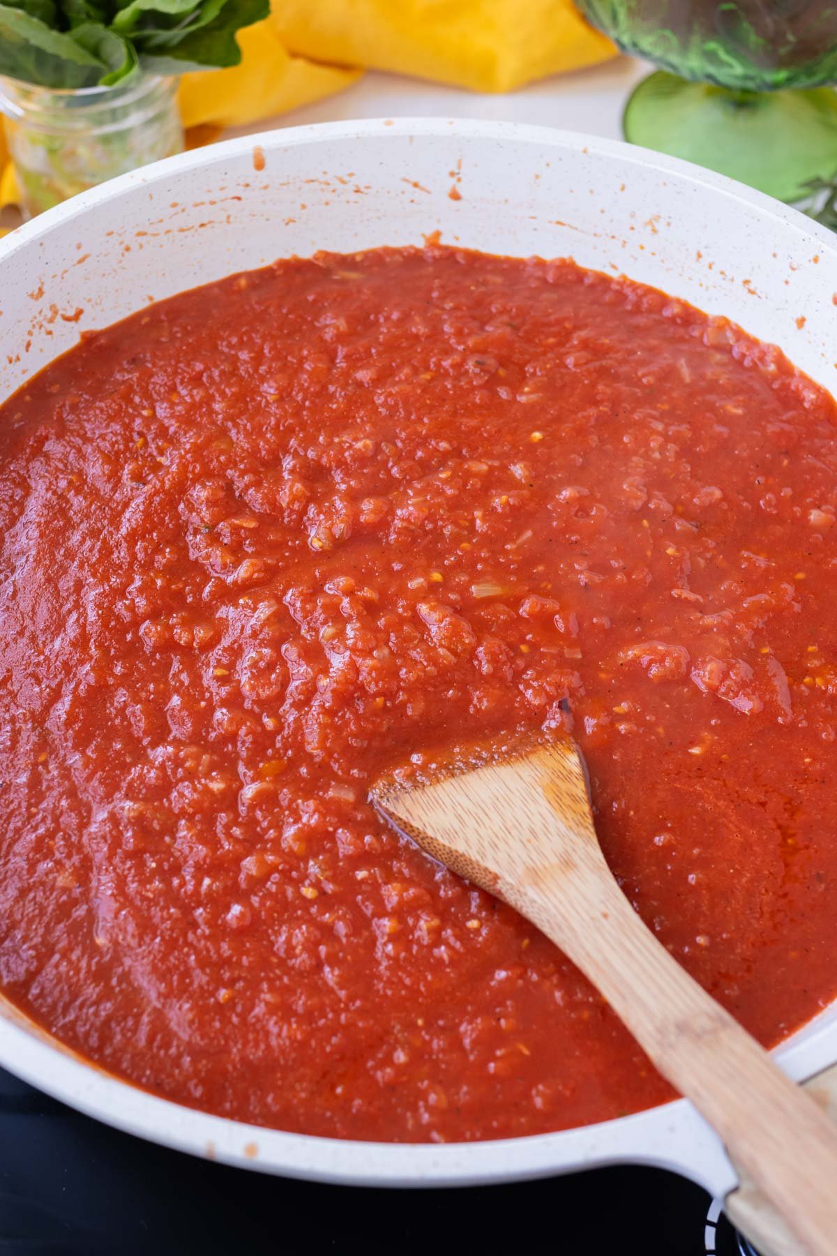 Processed canned tomatoes are added to the cooked shallots and garlic for a tomato sauce recipe.