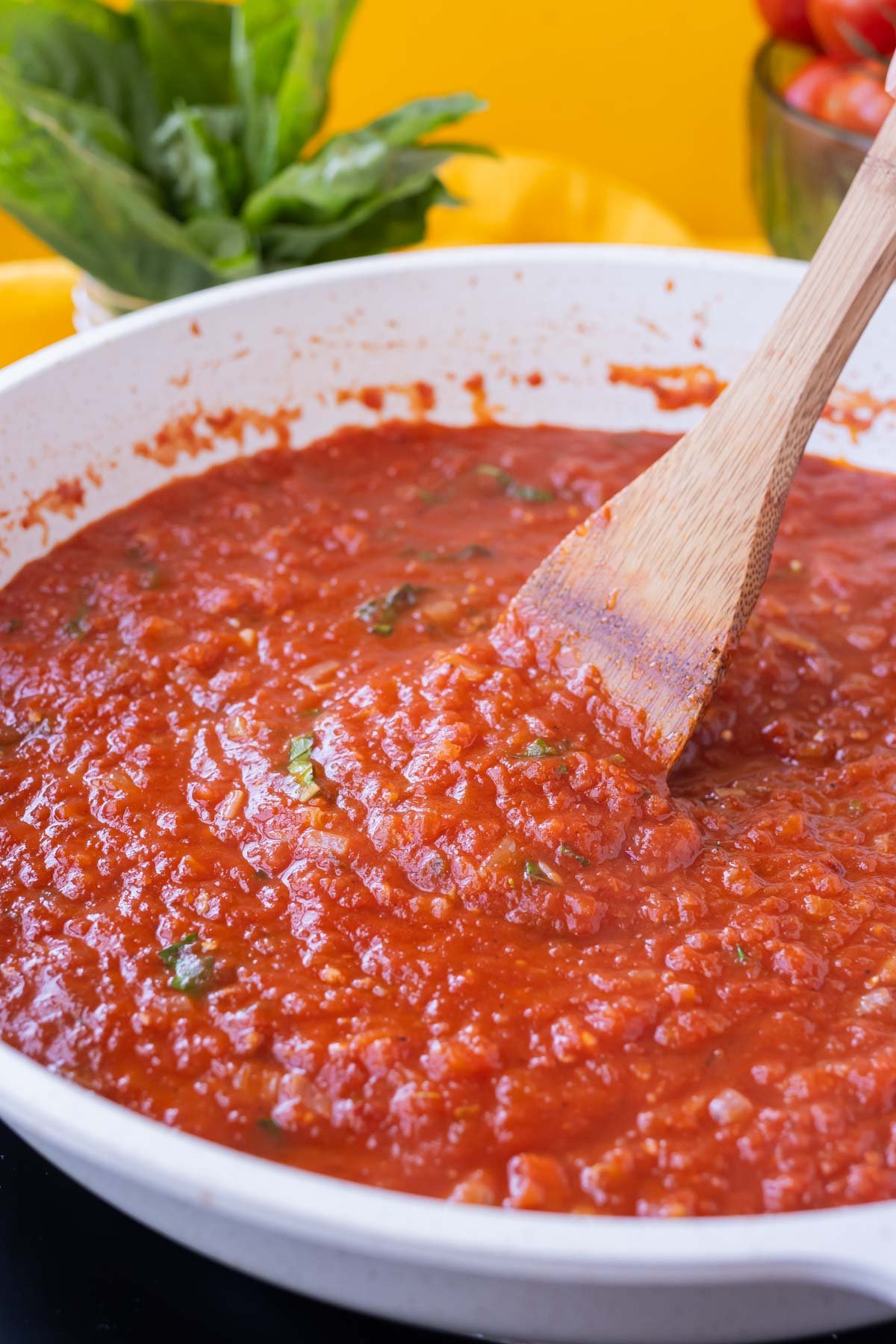 San Marzano tomato sauce is cooked in a big pot and stirred with a wooden spoon.