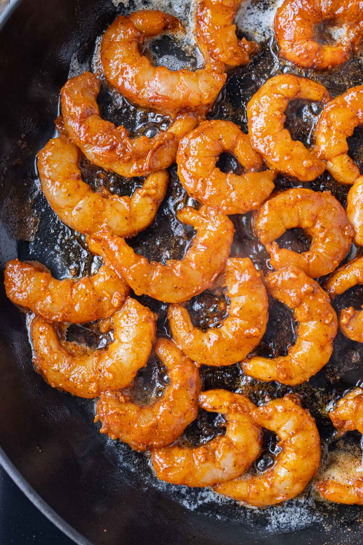 Seasoned shrimp are cooked in a skillet.