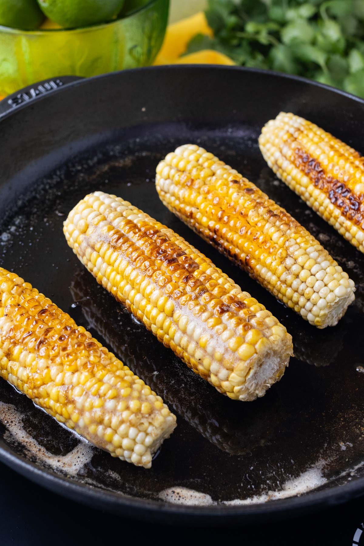 Corn on the cob is charred in a skillet.