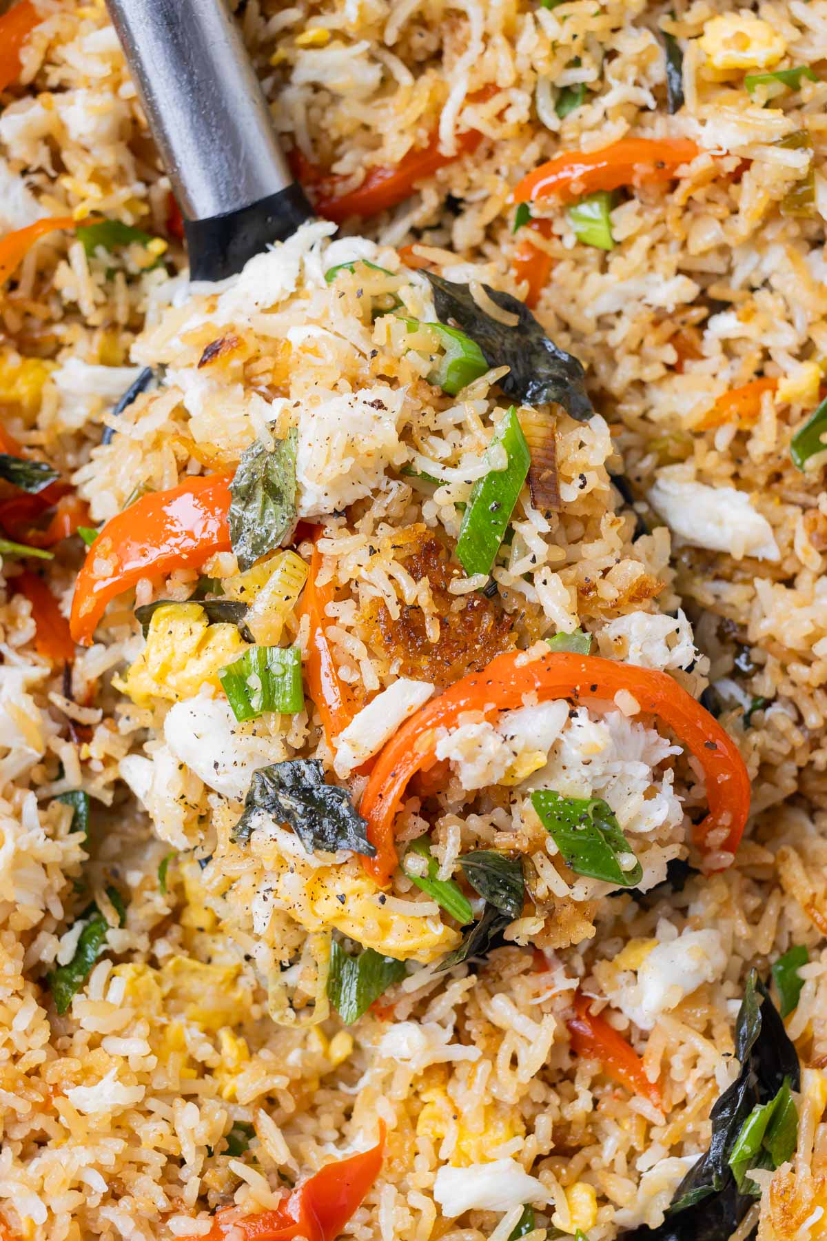 A spatula scoops up a serving of Thai Crab Fried Rice from a wok.