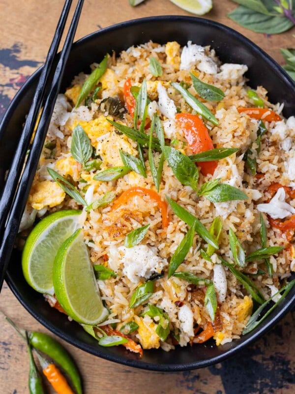 A bowl of Thai Crab Fried Rice with bell peppers, Thai basil, and lump crab meat is served with chopsticks.