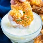 A fried coconut shrimp is being dipped into a piña colada sauce recipe like Red Lobster's.