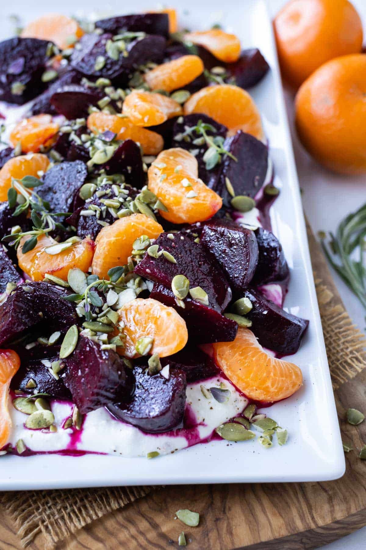 A platter is served with roasted red beets, orange pieces, honey, and whipped goat cheese.