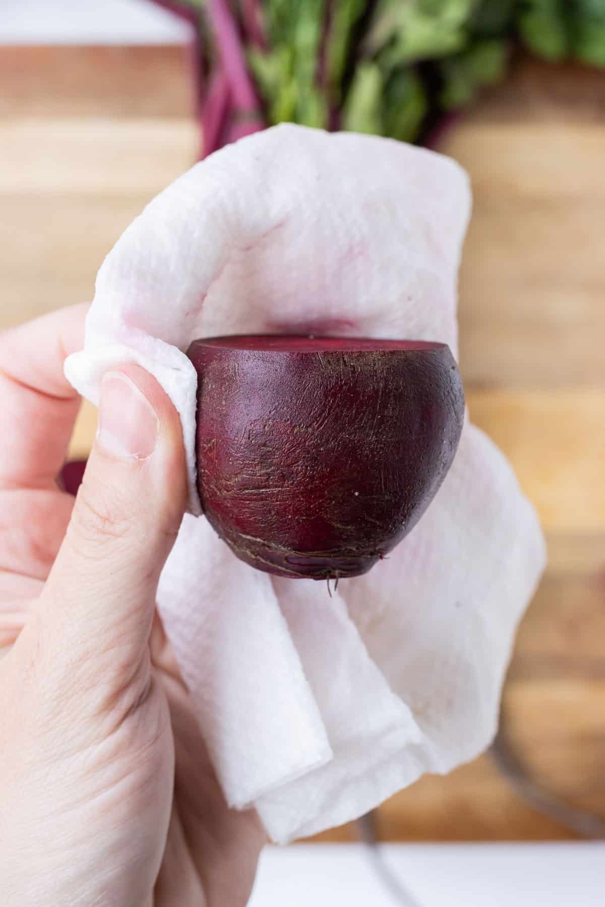 A beet is prepped before roasting.