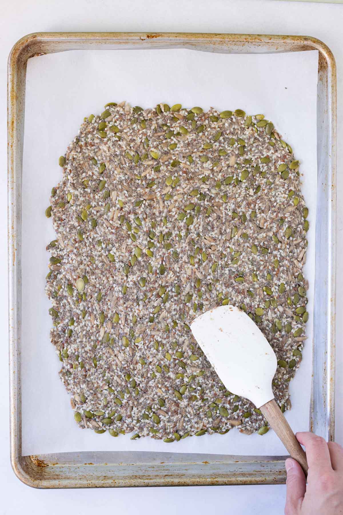 The cracker base is spread on a baking sheet before cooking.