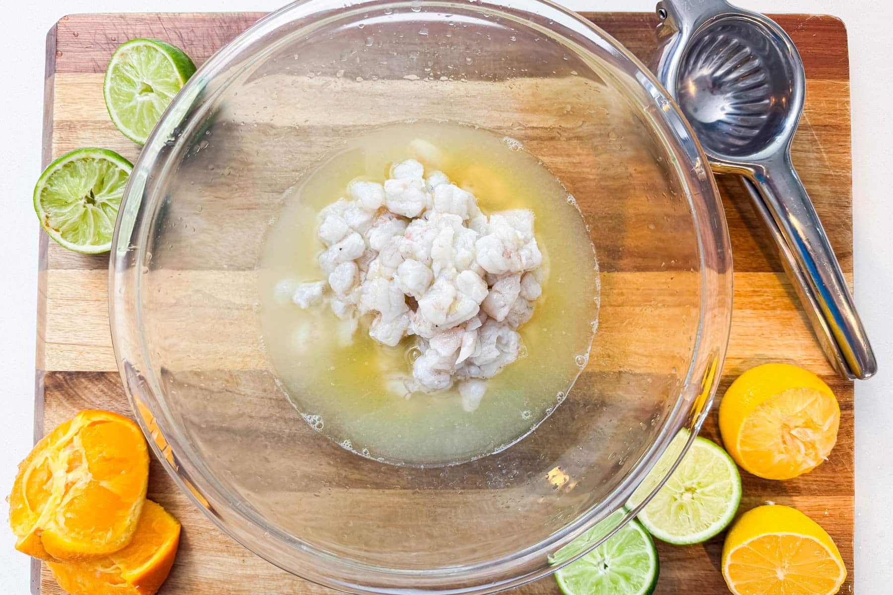 Shrimp being added to a bowl of citrus juice marinade for a ceviche recipe.