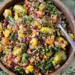 A wooden bowl is full of a Warm Fall Quinoa Salad with kale, roasted cauliflower and sweet potatoes and an apple cider vinaigrette.
