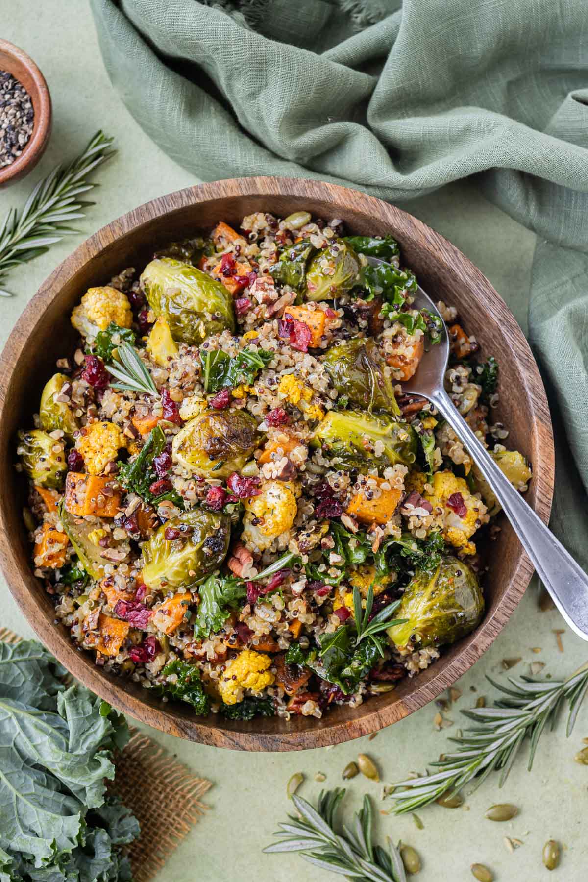 A metal spoon is used to dig into a big serving of a Fall quinoa salad with kale and roasted veggies.
