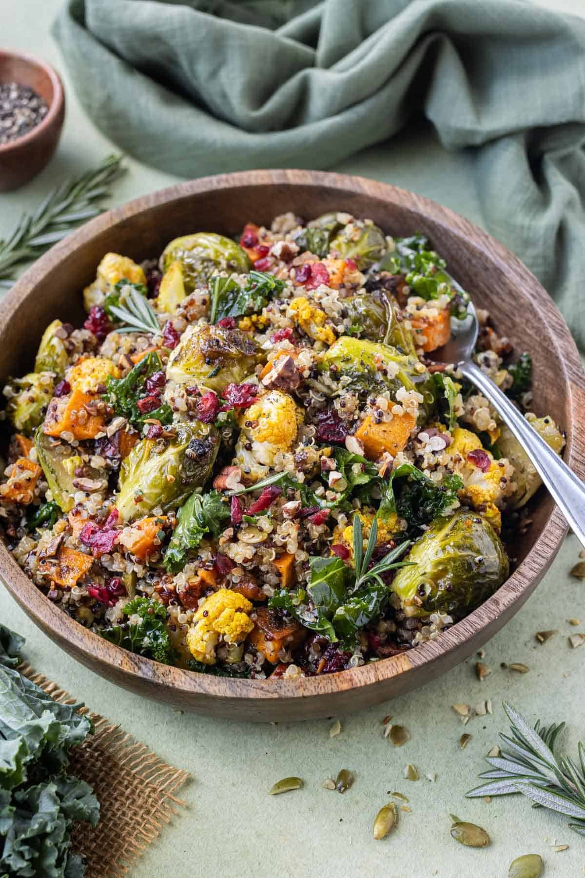 A warm Fall quinoa salad with a homemade apple cider vinaigrette is served in a wooden bowl.