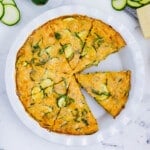 A cheesy zucchini pie has been cut into wedges for serving.