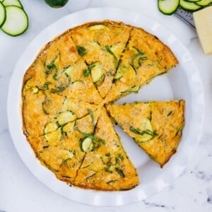 A cheesy zucchini pie has been cut into wedges for serving.