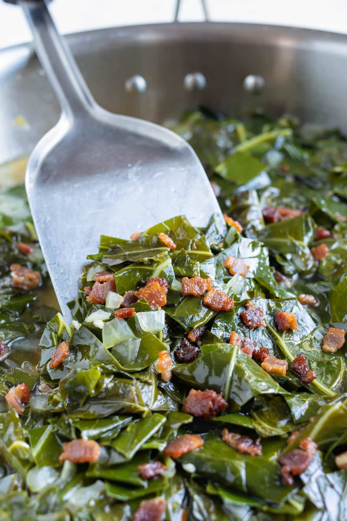 A pan in shown with cooked southern collard greens and bacon.