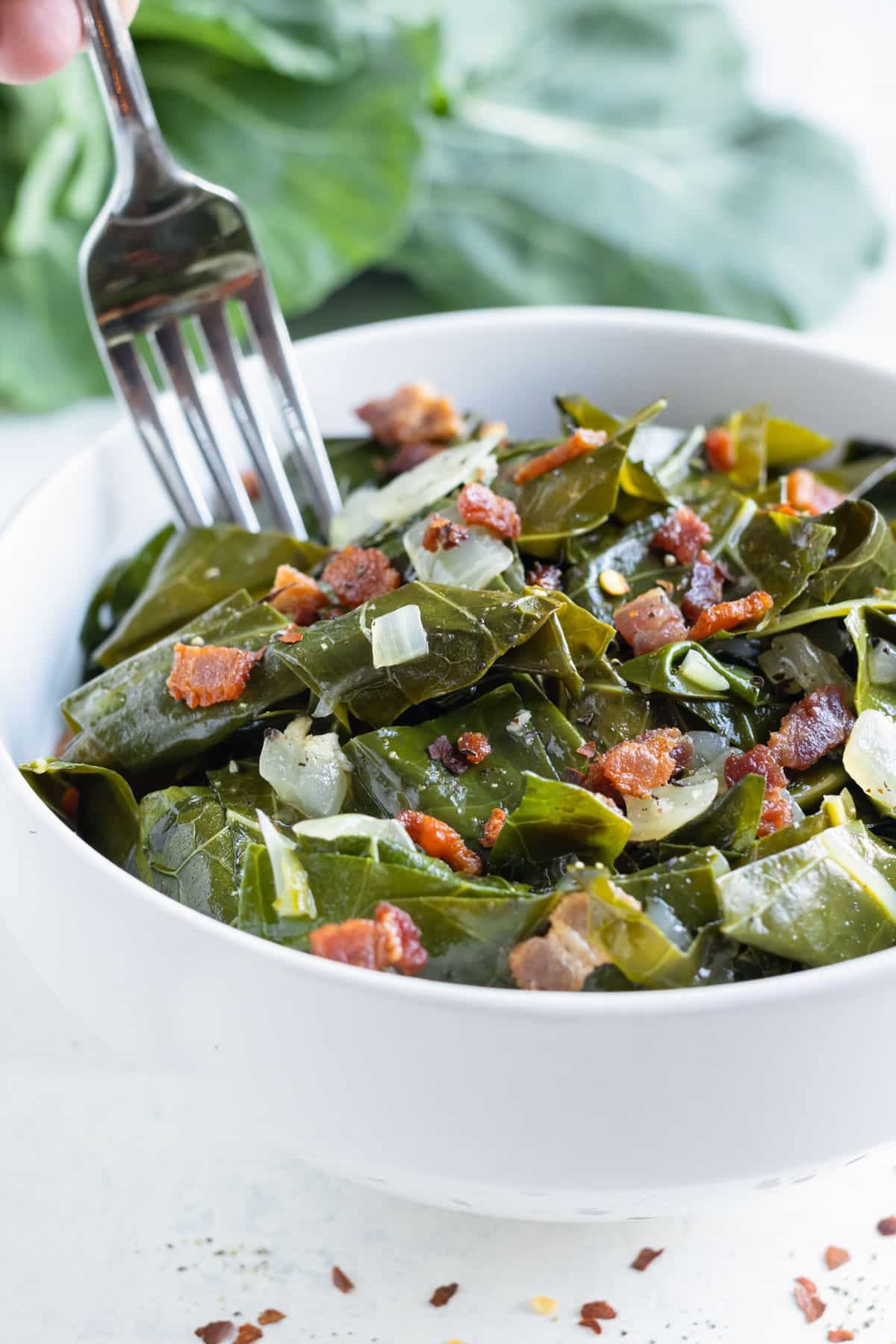 A fork is shown eating collard greens.