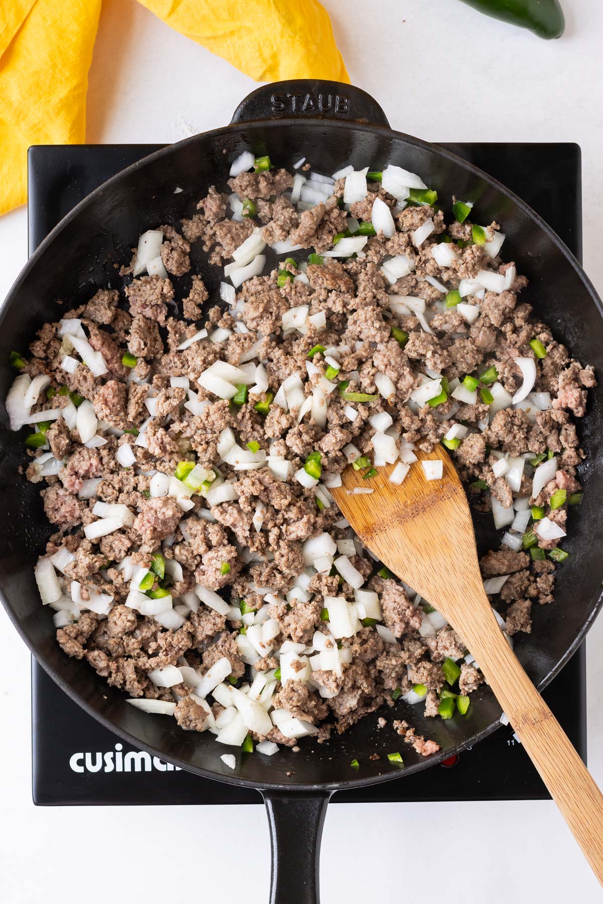Beef and veggies are cooked in a cast iron skilet.