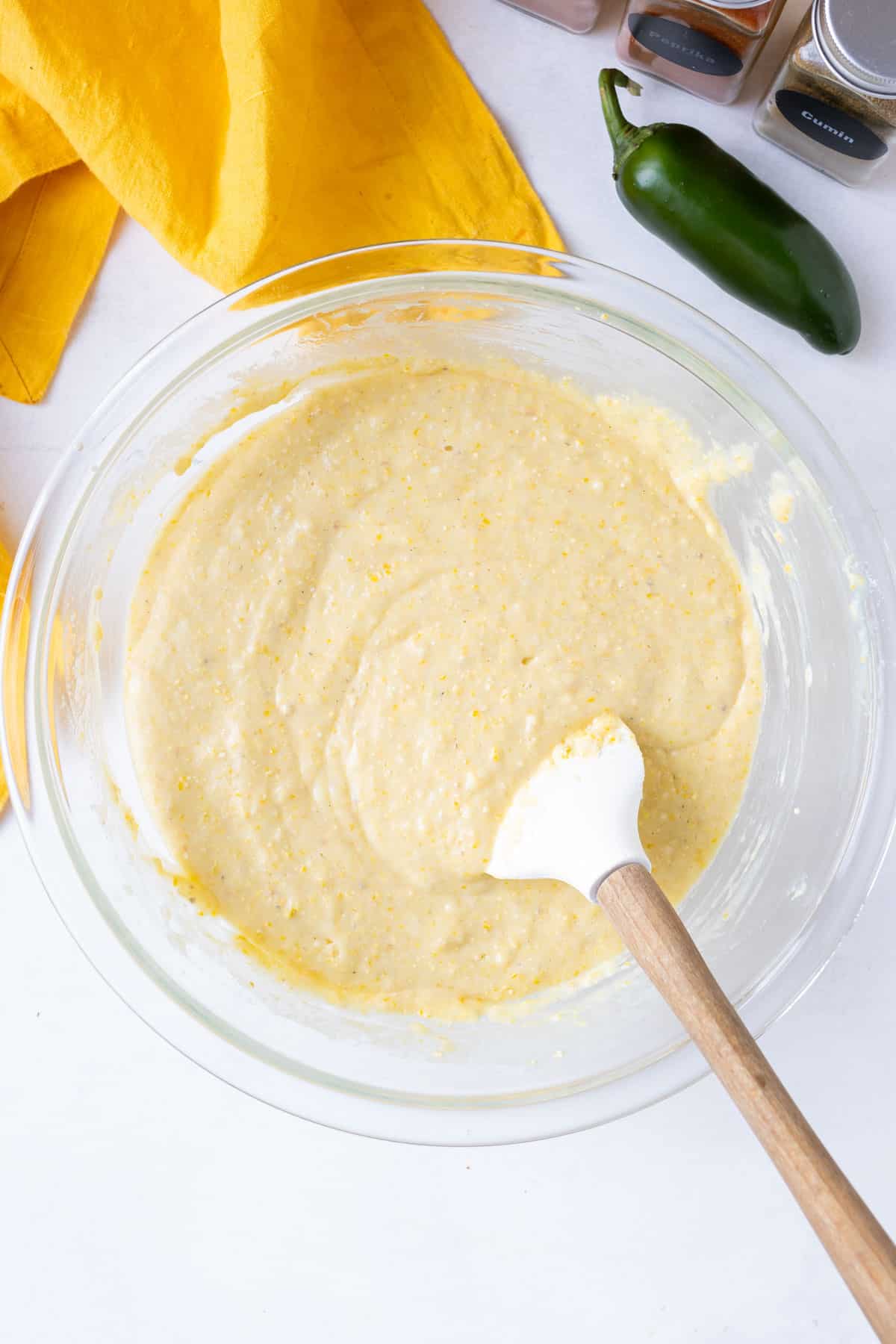 The homemade cornbread base is stirred together with a spatula.