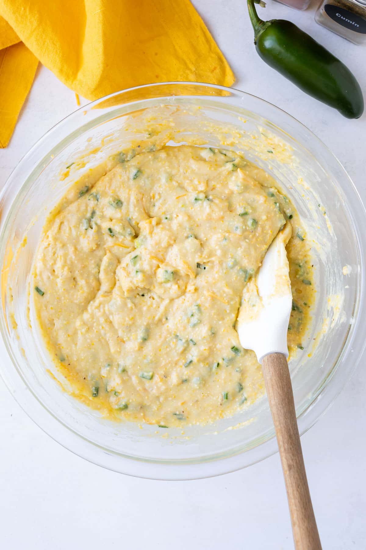 A spatula stirs together a jalapeno honey cornbread mixture.