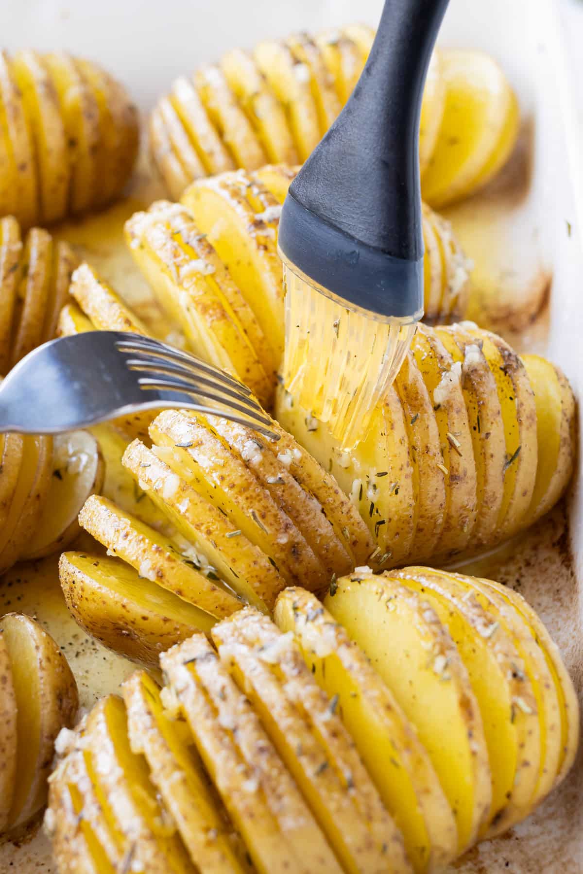A fork separates the pieces of the potatoes to brush the seasoning into it.