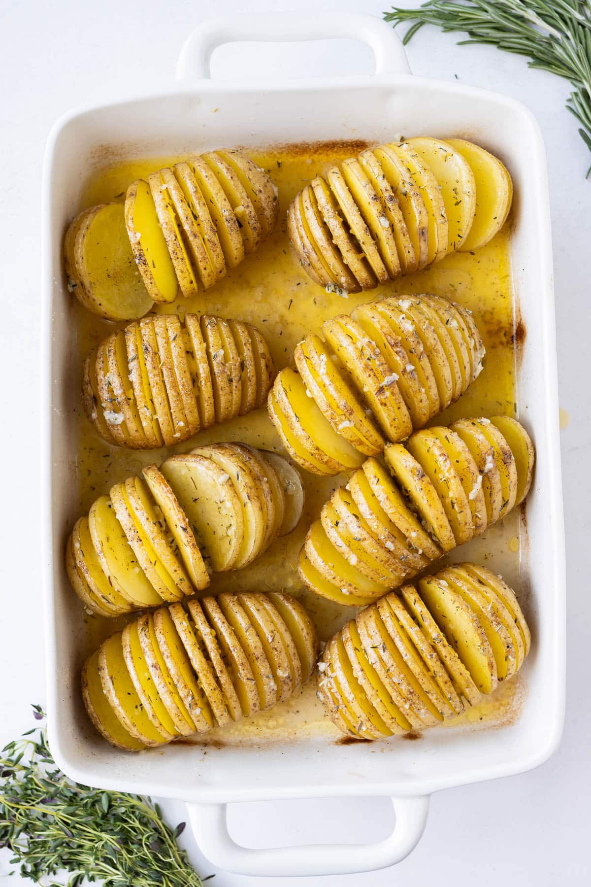 A deep baking dish is filled with Hasselback potatoes before baking.