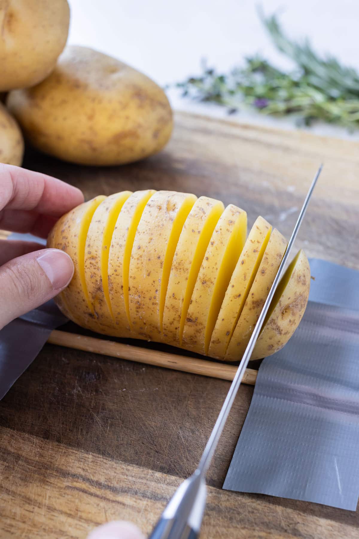 A sharp knife slices into a Yukon gold potato.