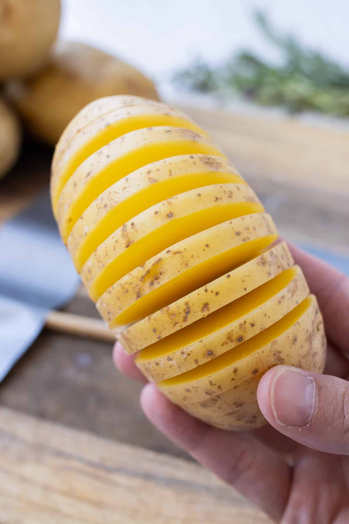 A hand shows how a Yukon gold potato is sliced.