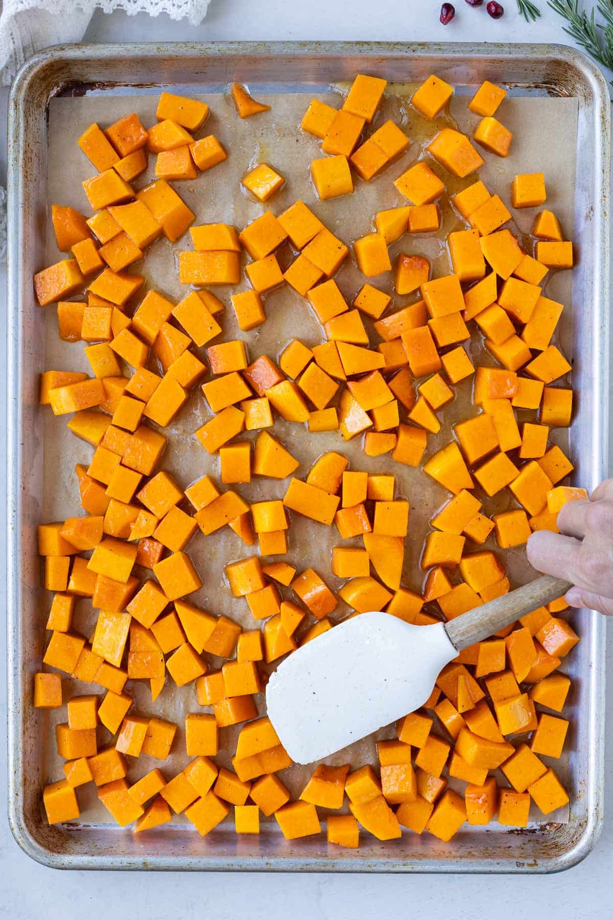 Butternut squash cubes are on a baking sheet before roasting.