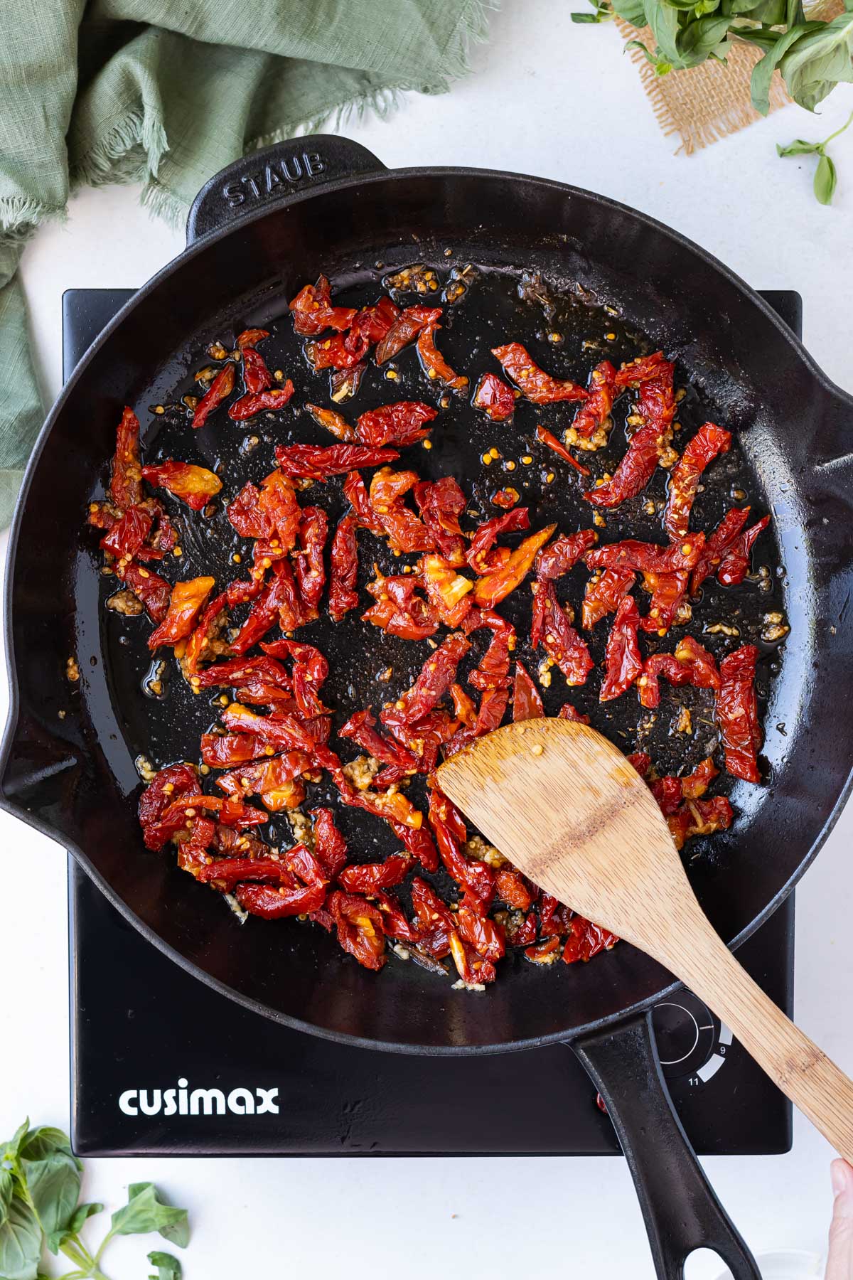 Sun-dried tomatoes and garlic are cooked in a cast iron skillet.