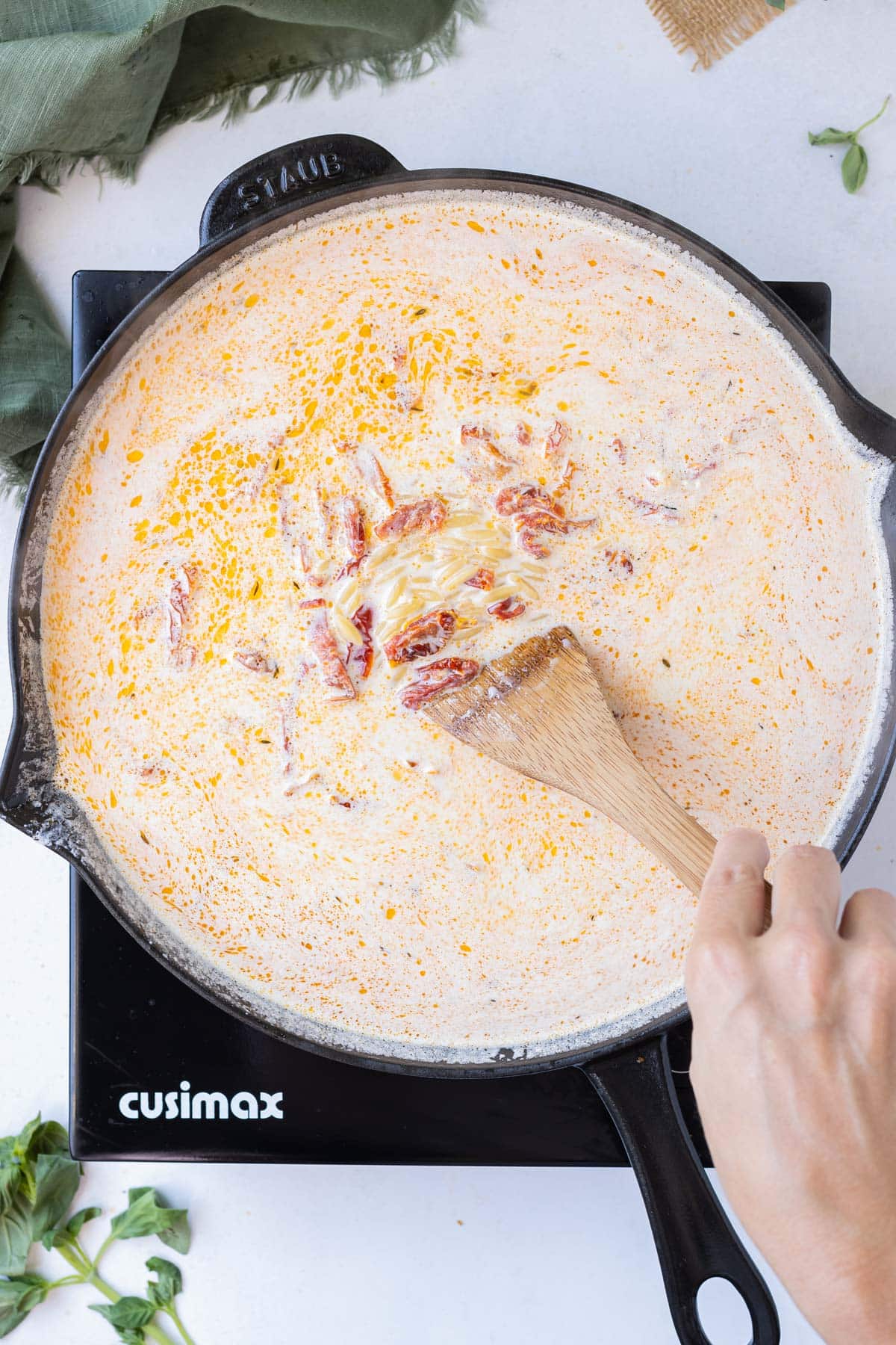 Cream, broth, and orzo are added to the sun-dried tomatoes.