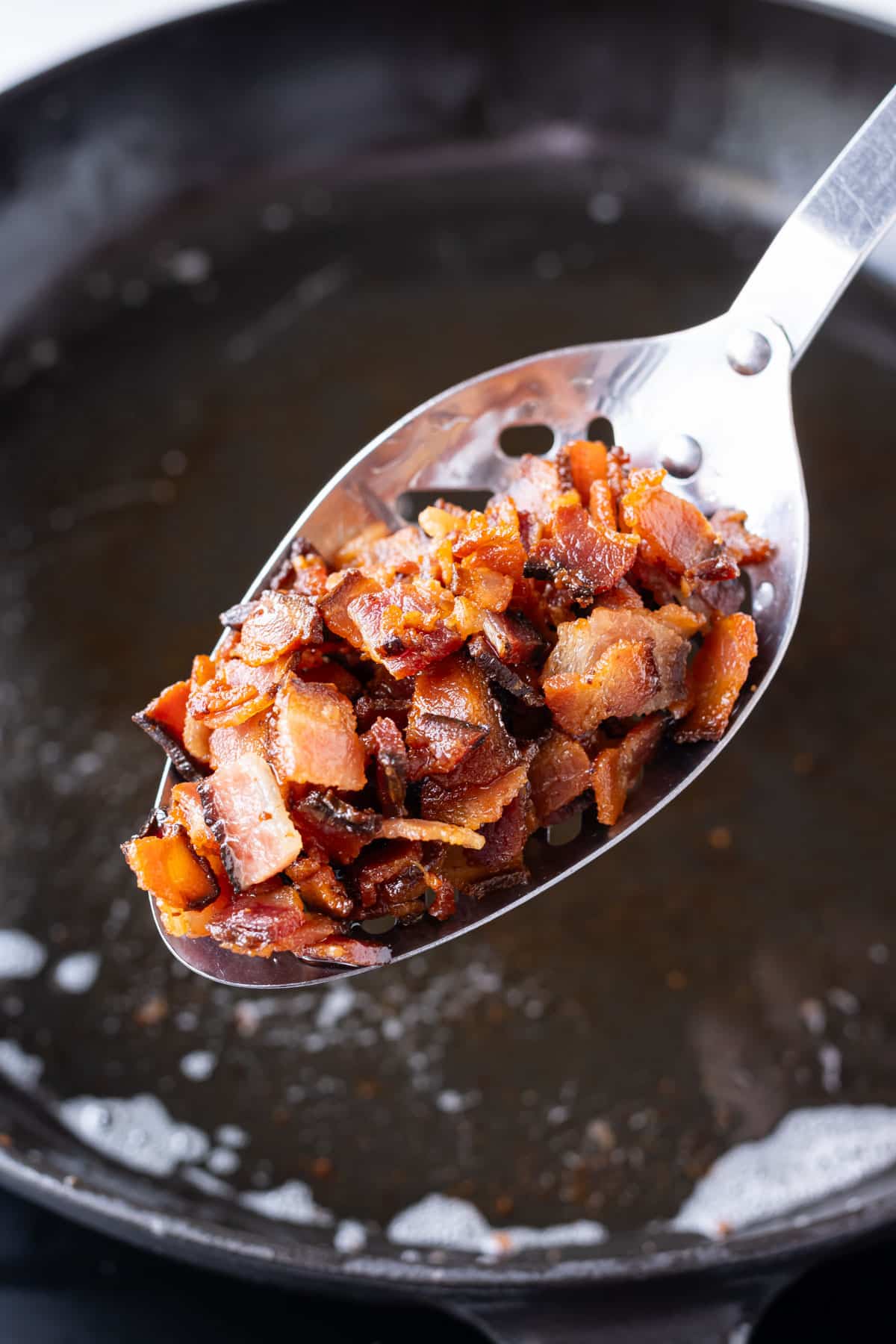 Bacon pieces are cooked in a skillet.