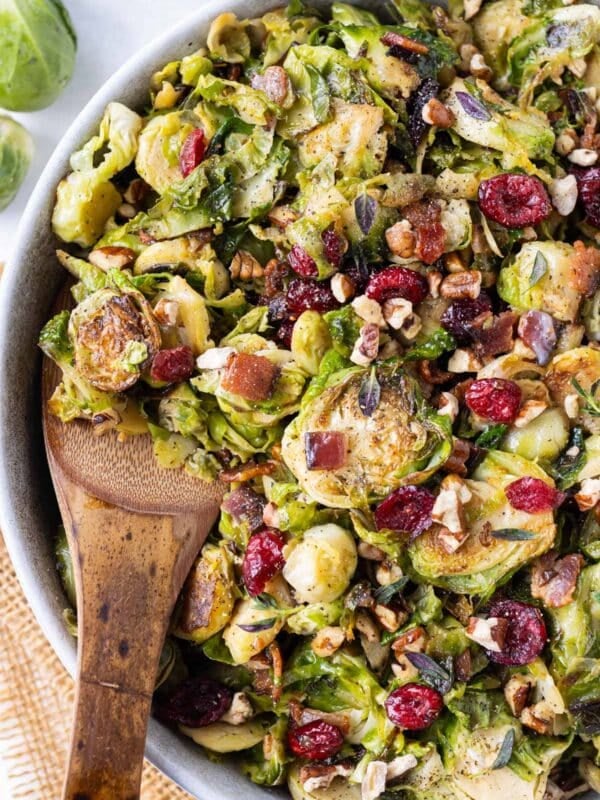 A salad bowl full of Maple Bacon Shredded Brussels Sprouts is served with a spoon for dinner.