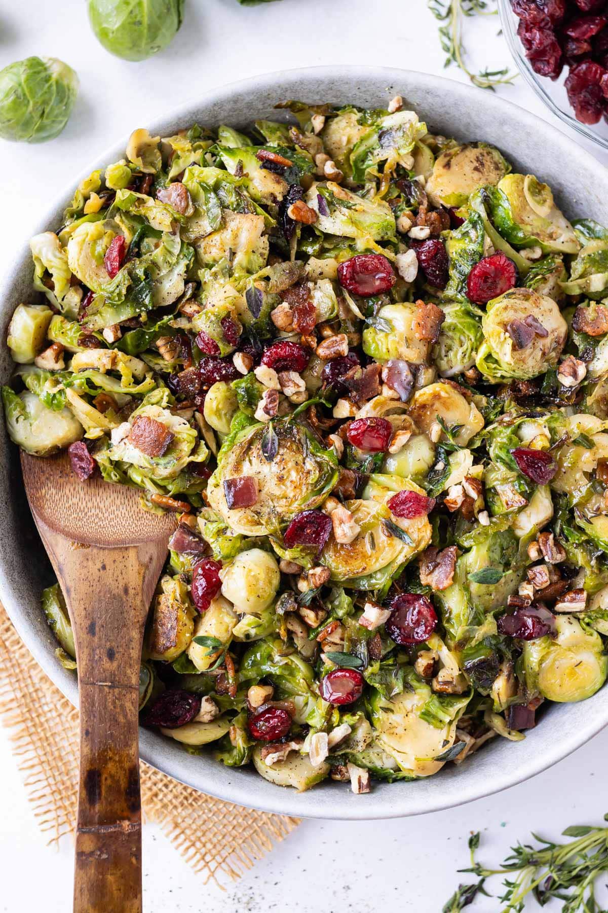 A serving spoon scoops up some shredded Brussels sprouts salad with bacon, cranberries, and pecans.
