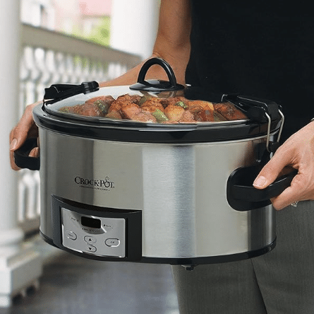 A lady holding a 6-quart Crockpot slow cooker.