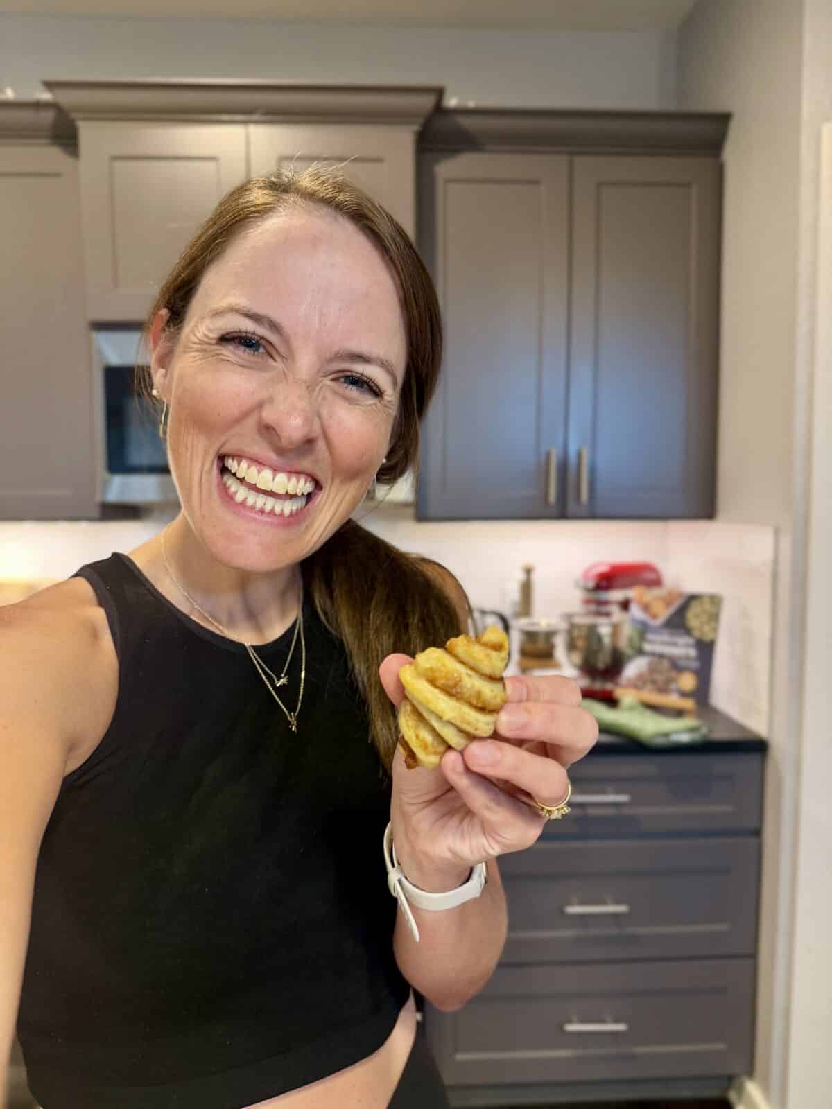 London Lea is holding a mini cinnamon roll croissant in her kitchen while recipe testing.