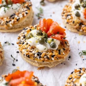 Salmon Cream Puffs with an everything bagel seasoning, capers, and dill are on a platter for serving at a party.