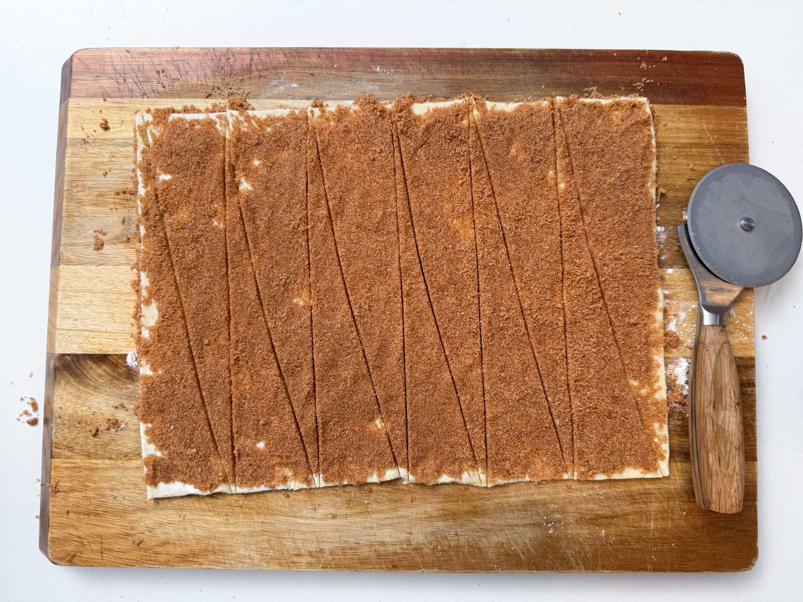 A cinnamon mixture is spread over puff pastry that is cut into triangles to make croissants.