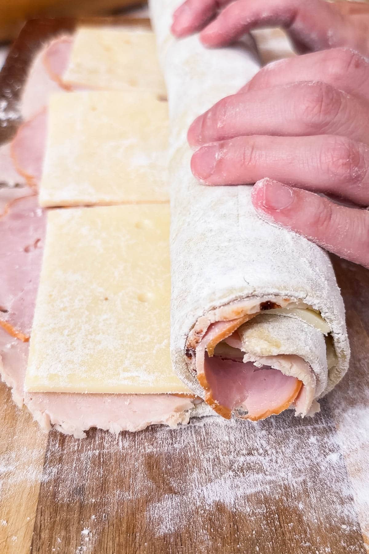 The puff pastry with meat and cheese is rolled up tight.